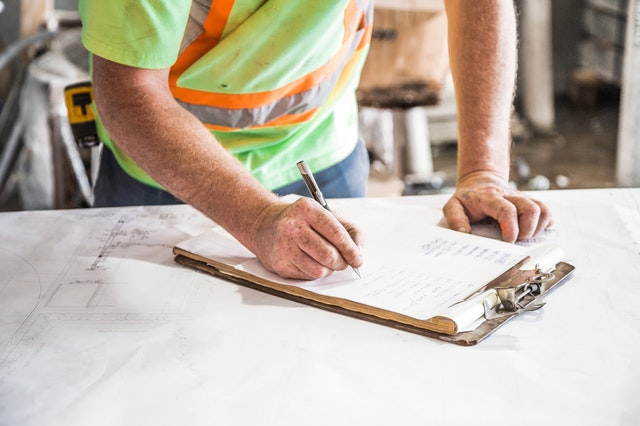 construction worker filling out form on clipboard